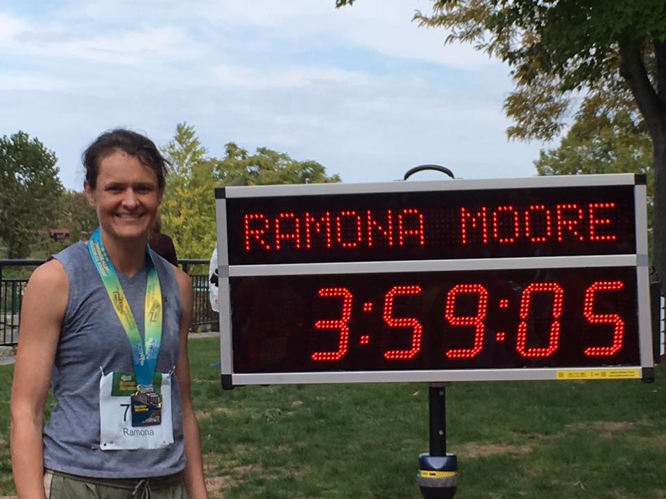 Ramona M standing at the finish line wearing metal after running a race